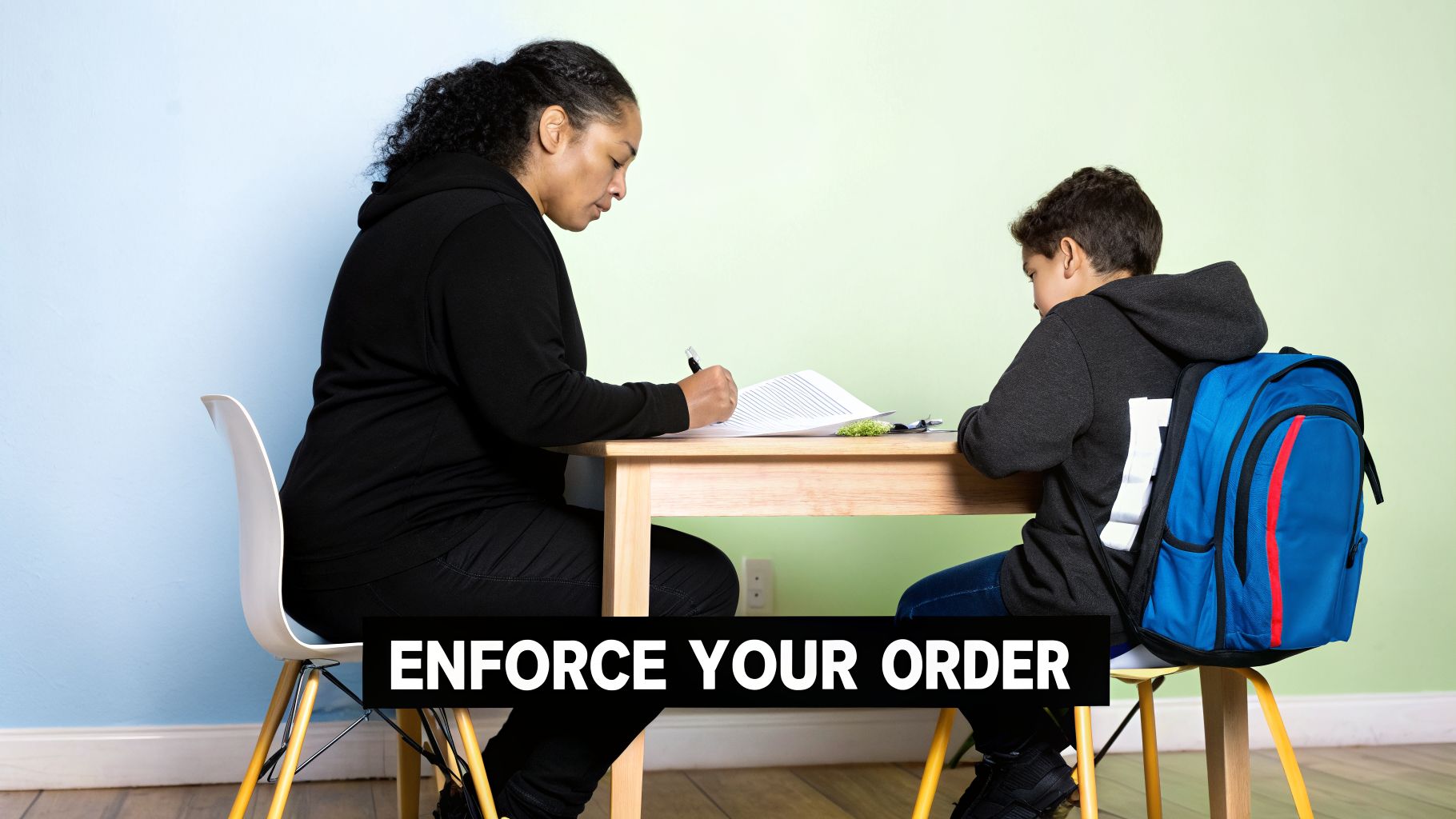 An adult woman and a young boy are seated at a wooden desk, engaged in a study session.