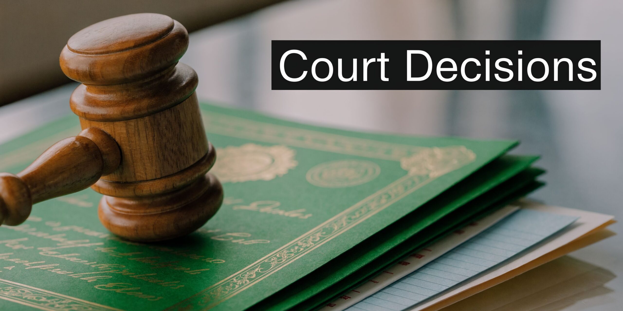 A wooden judge's gavel resting on top of a stack of important legal documents and certificates.