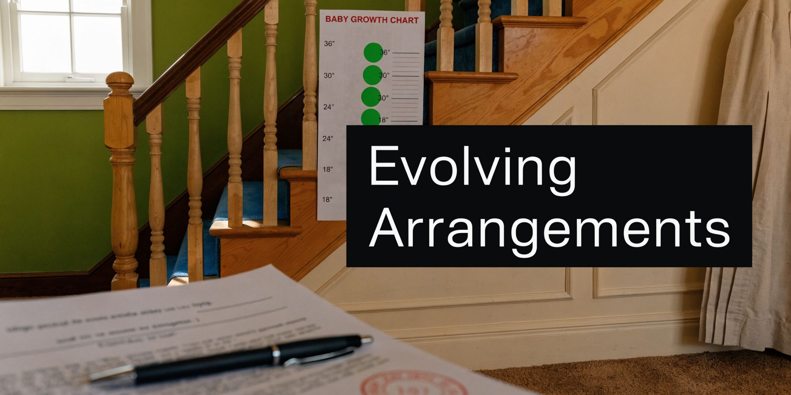 A document and pen are on a table near stairs featuring a baby growth chart on the wall.