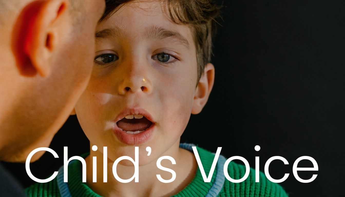 A close-up shot of a parent whispering into the ear of a young, attentive child.