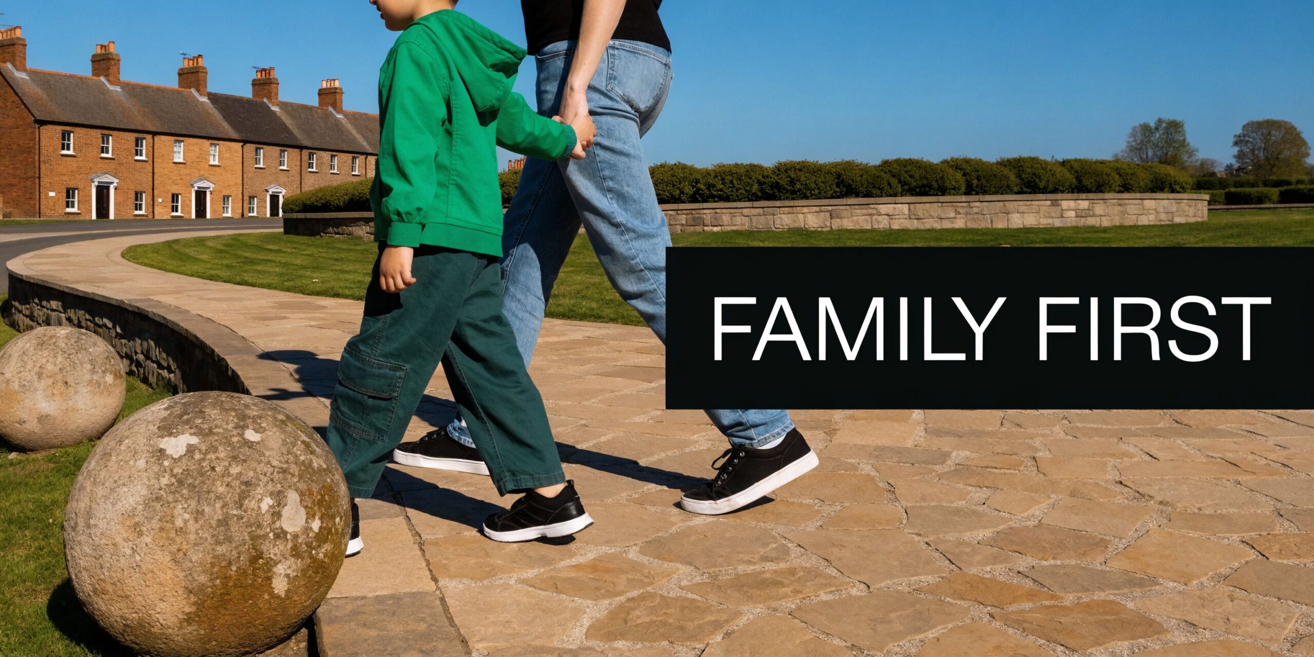 A young child in a green hoodie holding hands with a parent while walking outdoors.