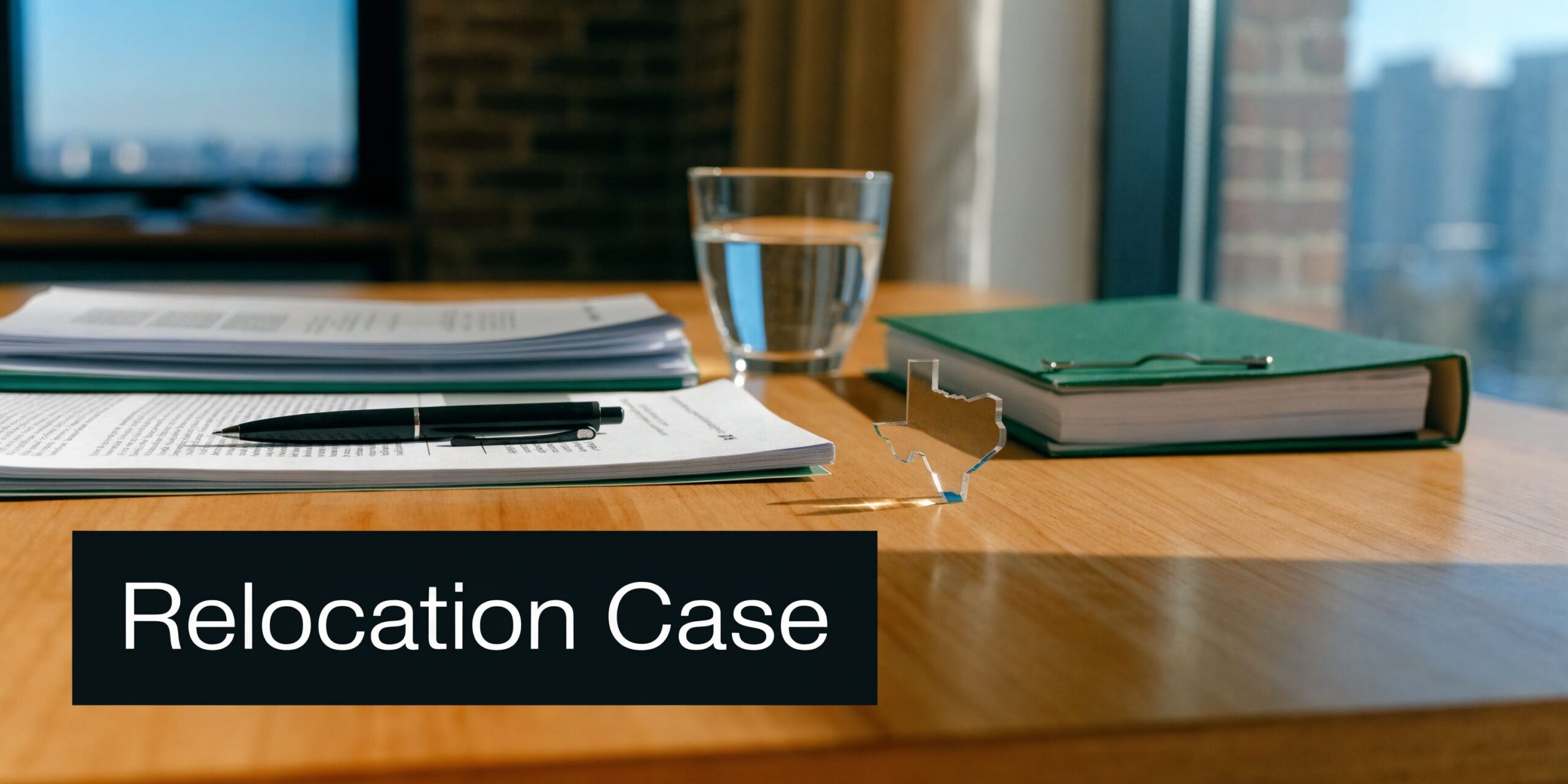 A legal desk setup with documents, a pen, and a small glass model of Texas.