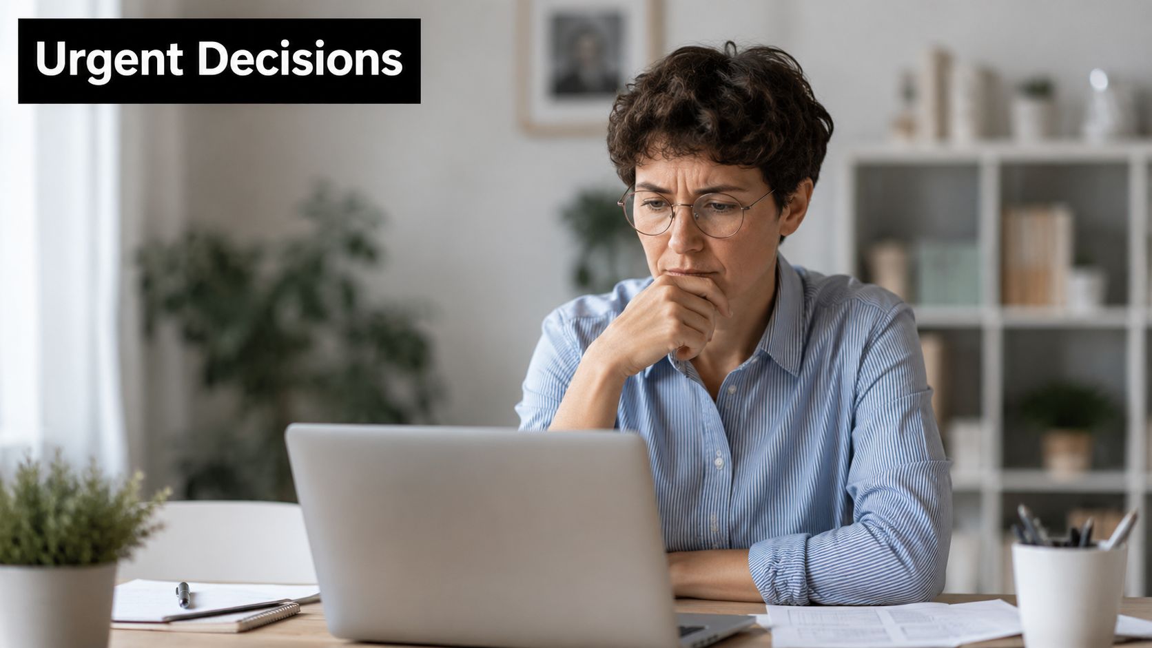 A focused professional woman sitting at a desk with a laptop, looking concerned while making urgent decisions.